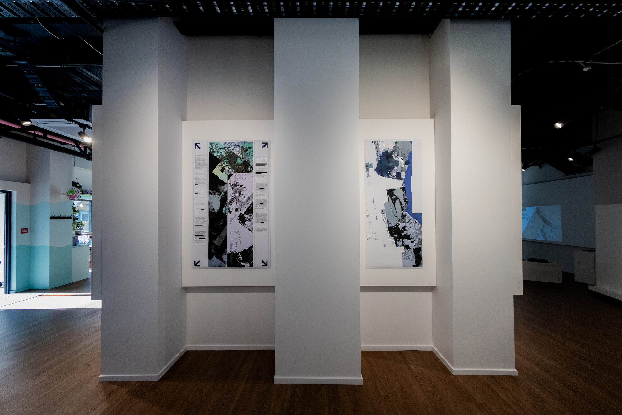 Two plates hung between the gallery columns, essay panel facing ice plate